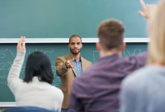 pädagoge steht vor einer klasse, beantwortet fragen der studierenden und vermittelt inhalt für das paeddr-doktorat im fernstudium